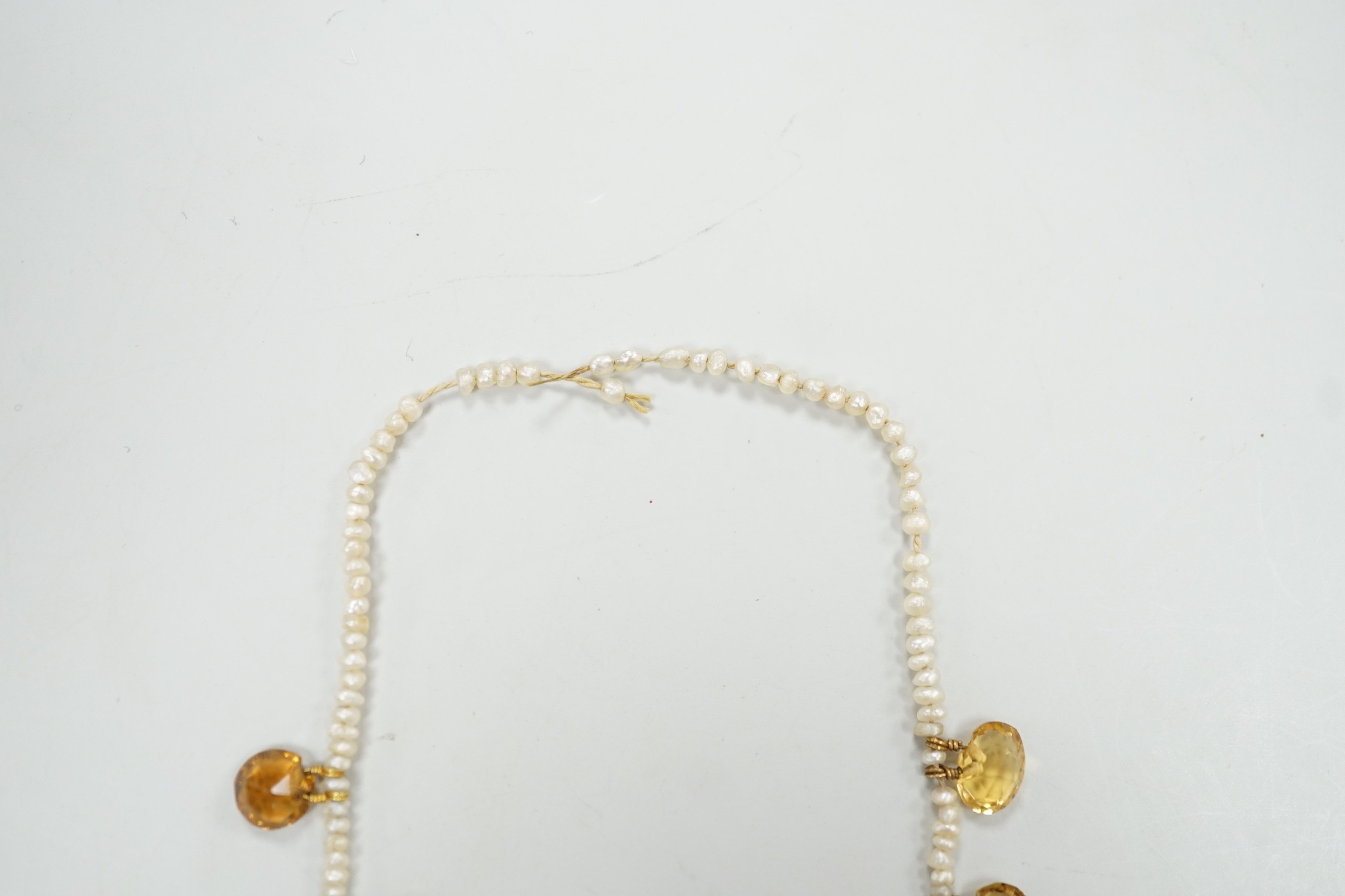 An Edwardian twenty one graduated oval cut citrine set seed pearl necklace (a.f) clasp loose, approx. 34cm.